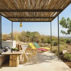 Porches sencillos y bonitos con mesa de piedra, asientos cómodos y tumbonas coloridas, disfrutando de vistas al campo.