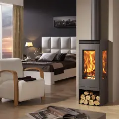 Estufa de leña moderna con fuego encendido, junto a una cama y sillón. Diversos tipos de estufas de gas ofrecen alternativas eficientes.
