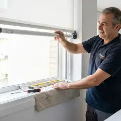 Técnico instalando motor para automatizar persianas eléctricas. Herramientas y móvil con app de control a la vista.