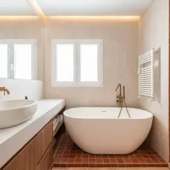 Baño moderno con bañera exenta y ducha. La iluminación indirecta en el techo y la luz natural de la ventana ayudan a como iluminar un baño.