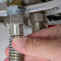 Burbujas de jabón indican que la caldera pierde agua apagada. Una mano toca la fuga.