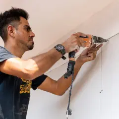 Hombre taladrando una pared de pladur, asegurando la correcta distancia entre perfiles.