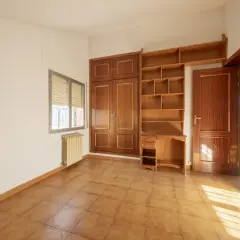Habitación con armario y estanterías de madera. Las puertas sapelly cambiar color con la luz, creando un ambiente cálido.