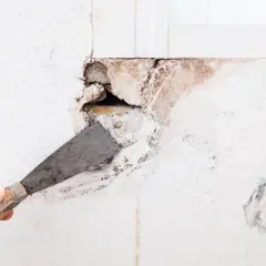 Mano con espátula preparando una pared para tapar agujeros.