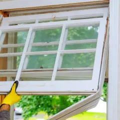 Manos enguantadas retiran un panel de ventana antiguo, imaginando cómo sería cuando se inventó el cristal para las ventanas.