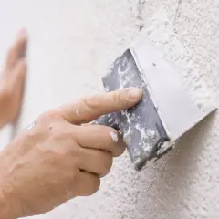 Mano aplicando masilla con espátula para reparar gotelé.