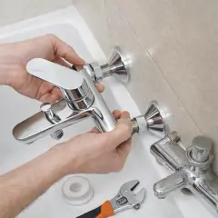 Man installing a new shiny grifo bañera. A wrench and tape are nearby.