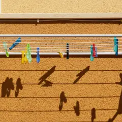Variedad de pinzas de colores sujetan la ropa en distintos tipos de tendederos exteriores. Las sombras proyectadas crean un patrón interesante.