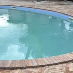 Agua blanca y cristalina en una piscina, rodeada por un borde de ladrillos. El reflejo del cielo en el agua invita a un refrescante chapuzón.