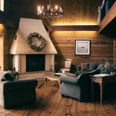 Salón rústico con chimenea de obra decorada con corona de hojas. Sofás cómodos y suelo de madera invitan a relajarse.