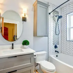 Moderno baño con lavabo, inodoro y una bañera o ducha con azulejos de espiga.