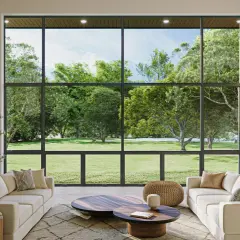 Salón moderno con sofás blancos y chimenea, enmarcado por amplias paredes de cristal que ofrecen vistas a un exuberante jardín verde.