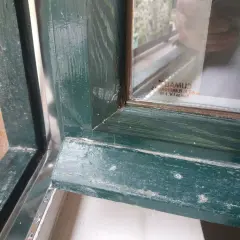 Detalle de marcos de madera antiguos pintados de verde, mostrando el proceso para aislar ventanas antiguas de madera y mejorar su eficiencia.