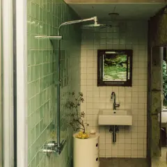 Baños pequeños con ducha, lavabo y espejo con vista a un jardín. Paredes de azulejos verdes y piedra natural.