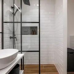 Modern bathroom with a glass-enclosed shower featuring white subway tiles and a built-in niche. The shower is adjacent to a wall, creating a functional space.