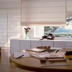 Estudio moderno con sillón, mesa y varios tipos de persianas romanas que filtran la luz del sol.