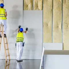 Trabajadores instalan paneles de yeso sobre materiales de aislamiento acustico, creando un ambiente más silencioso.