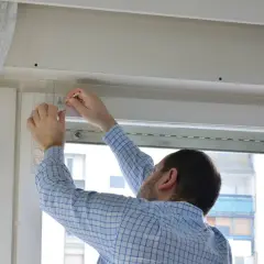 Hombre ajustando el mecanismo persiana enrollable cuerda con una regla.