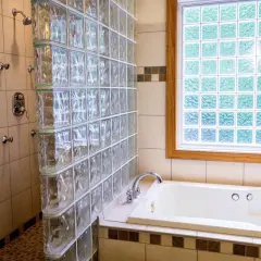 Duchas con paves de vidrio separan la bañera de la zona de ducha. La luz se filtra a través de la ventana de paves.