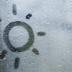 Sol dibujado en una ventana con gotas de condensación. Consejos para saber como evitar que las ventanas sudan en invierno.