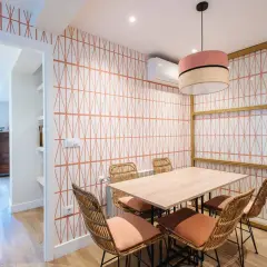 Comedor con papel pintado de rombos naranjas, mesa de madera y sillas de mimbre. ¡Una idea genial para saber como poner papel pintado!