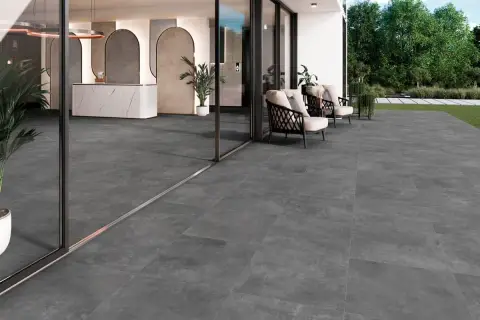 Amplia terraza con moderno suelo para terraza de gres porcelánico gris. Muebles de exterior y entrada acristalada.