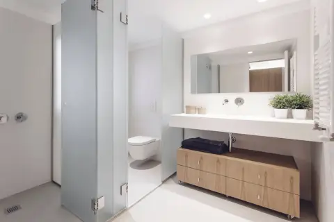 Baños modernos con ducha, inodoro y lavabo con mueble de madera.