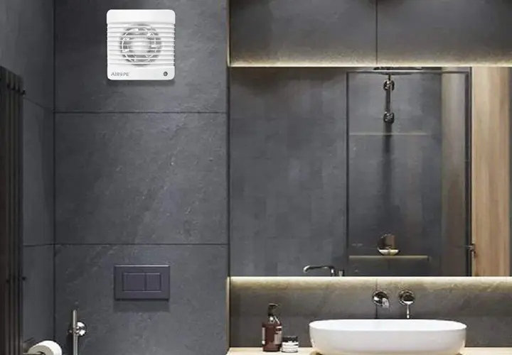 Extractor de baño blanco instalado en pared de azulejos grises.
