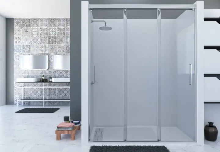 Mampara de ducha fija sin perfil inferior, con puertas correderas y rociador. Baño moderno con azulejos decorativos y lavabos dobles.
