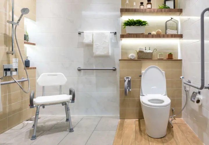 Baño moderno con duchas adaptadas para personas mayores, asiento de ducha, barras de apoyo y un inodoro.