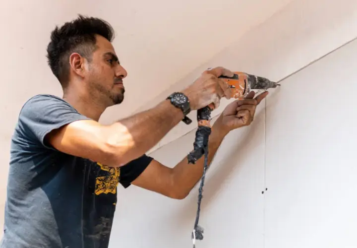Hombre taladrando una pared de pladur, asegurando la correcta distancia entre perfiles.