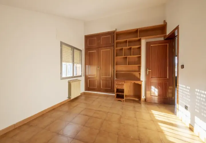 Habitación con armario y estanterías de madera. Las puertas sapelly cambiar color con la luz, creando un ambiente cálido.