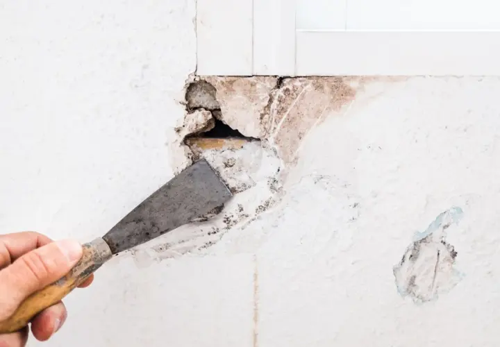 Mano con espátula preparando una pared para tapar agujeros.