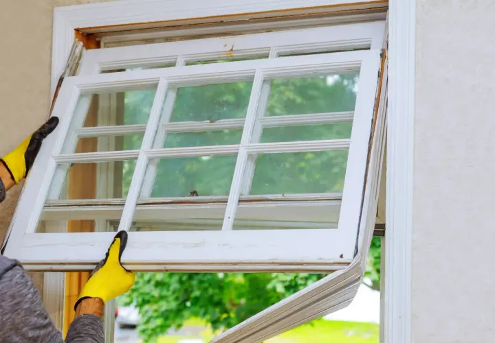 Manos enguantadas retiran un panel de ventana antiguo, imaginando cómo sería cuando se inventó el cristal para las ventanas.