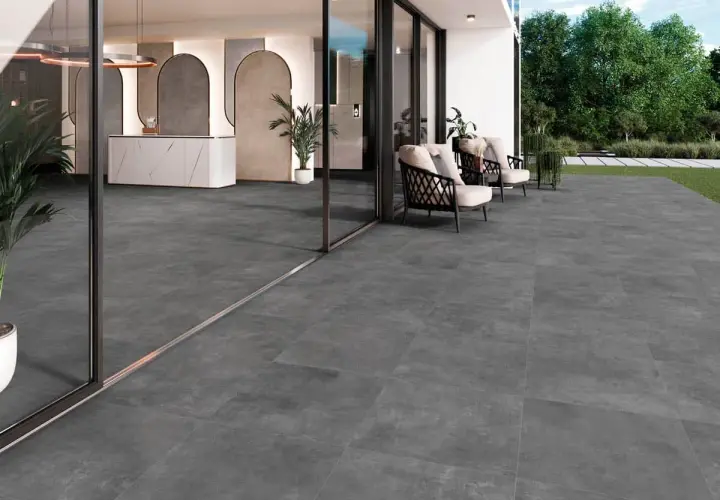 Amplia terraza con moderno suelo para terraza de gres porcelánico gris. Muebles de exterior y entrada acristalada.