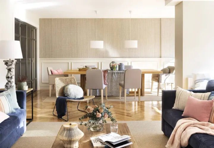 Un salón acogedor con sofás azules, una mesa de comedor de madera y una **beige color pared** con un patrón sutil.