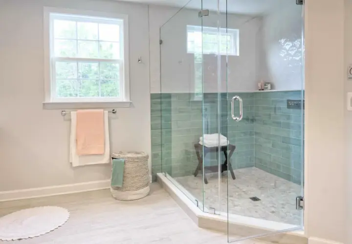 Instalar mampara ducha frontal corredera: baño moderno con ducha de cristal, azulejos verdes y ventana.