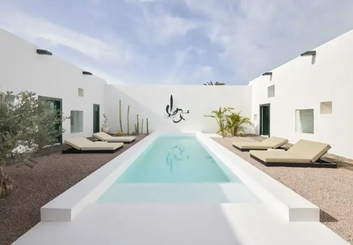 Patio minimalista con piscina, tumbonas y cactus. Ideas para decorar un patio con piscina y crear un oasis moderno.