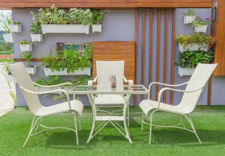 Un oasis verde en patios pequeños con césped artificial. Muebles blancos y plantas colgantes crean un rincón acogedor.