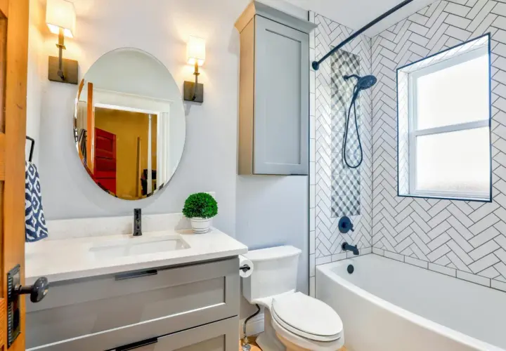 Moderno baño con lavabo, inodoro y una bañera o ducha con azulejos de espiga.