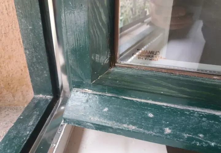 Detalle de marcos de madera antiguos pintados de verde, mostrando el proceso para aislar ventanas antiguas de madera y mejorar su eficiencia.