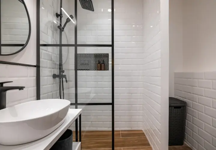 Modern bathroom with a glass-enclosed shower featuring white subway tiles and a built-in niche. The shower is adjacent to a wall, creating a functional space.