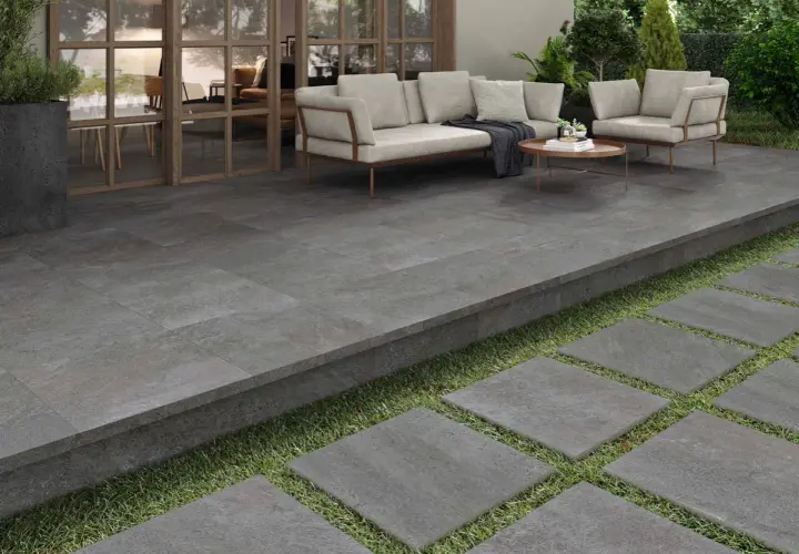 Terraza moderna con suelo de baldosas grises, ideal para pintar suelo terraza exterior. Muebles de exterior y plantas crean un oasis.