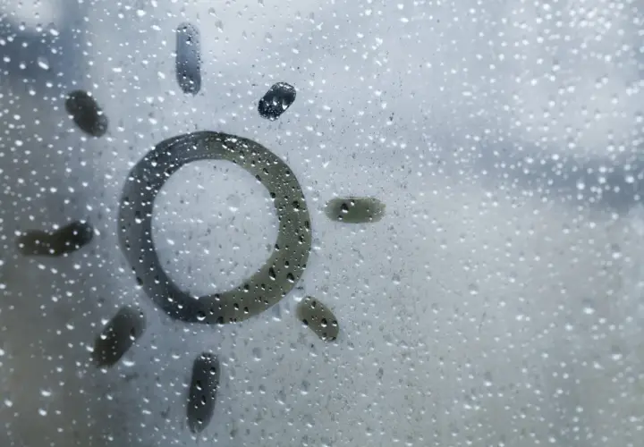 Sol dibujado en una ventana con gotas de condensación. Consejos para saber como evitar que las ventanas sudan en invierno.