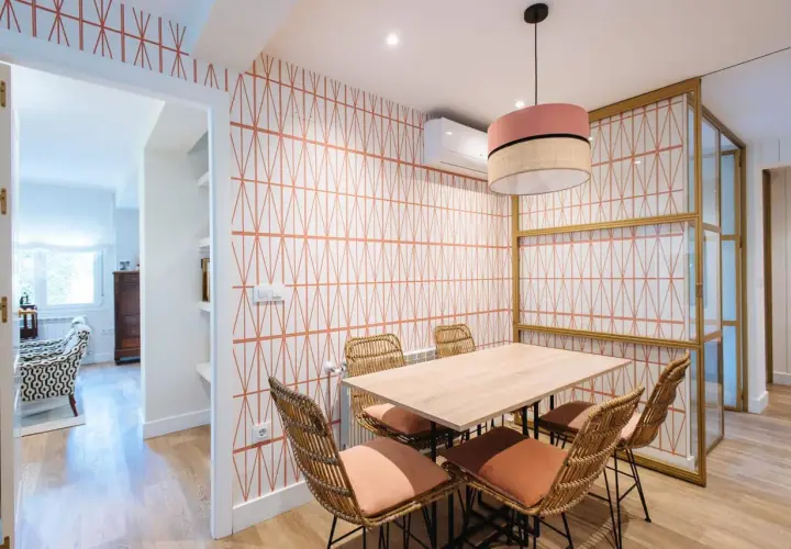 Comedor con papel pintado de rombos naranjas, mesa de madera y sillas de mimbre. ¡Una idea genial para saber como poner papel pintado!