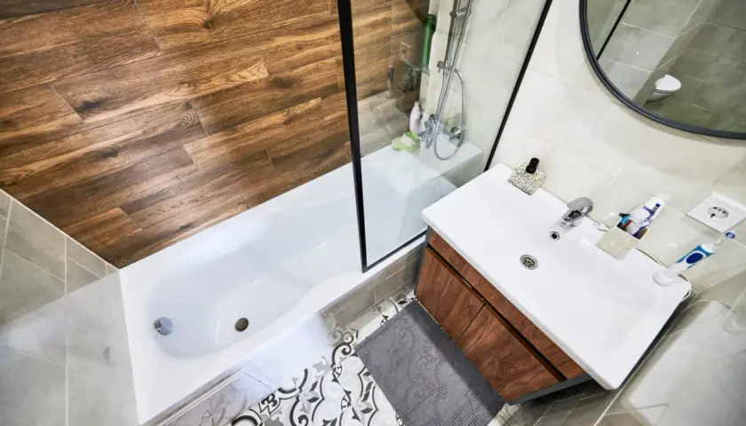 Baño moderno con ducha y bañera. Aprende como quitar una mampara pegada con silicona para renovar tu espacio.