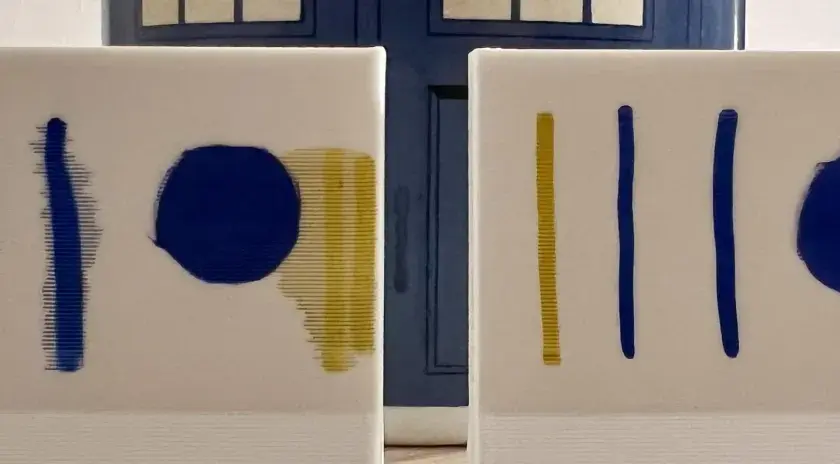 Dos lienzos blancos con trazos azules y amarillos. El fondo es una puerta azul, como si fuera una imprimación para un proyecto.