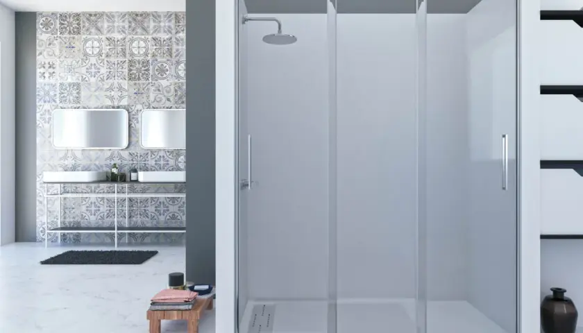 Mampara de ducha fija sin perfil inferior, con puertas correderas y rociador. Baño moderno con azulejos decorativos y lavabos dobles.