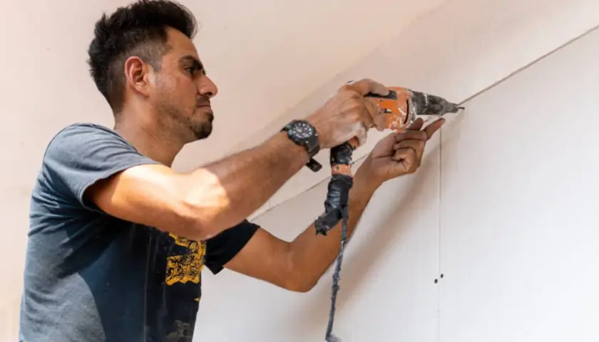 Hombre taladrando una pared de pladur, asegurando la correcta distancia entre perfiles.