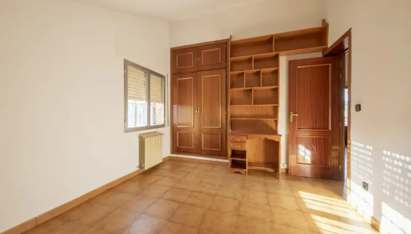 Habitación con armario y estanterías de madera. Las puertas sapelly cambiar color con la luz, creando un ambiente cálido.